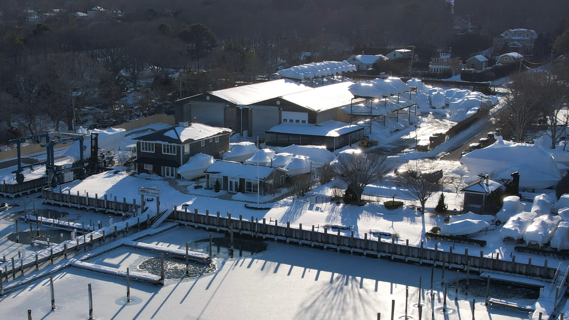 Aerial view of the snow-covered Modern Yachts marina with shrink-wrapped boats in winter boat storage on Long Island.