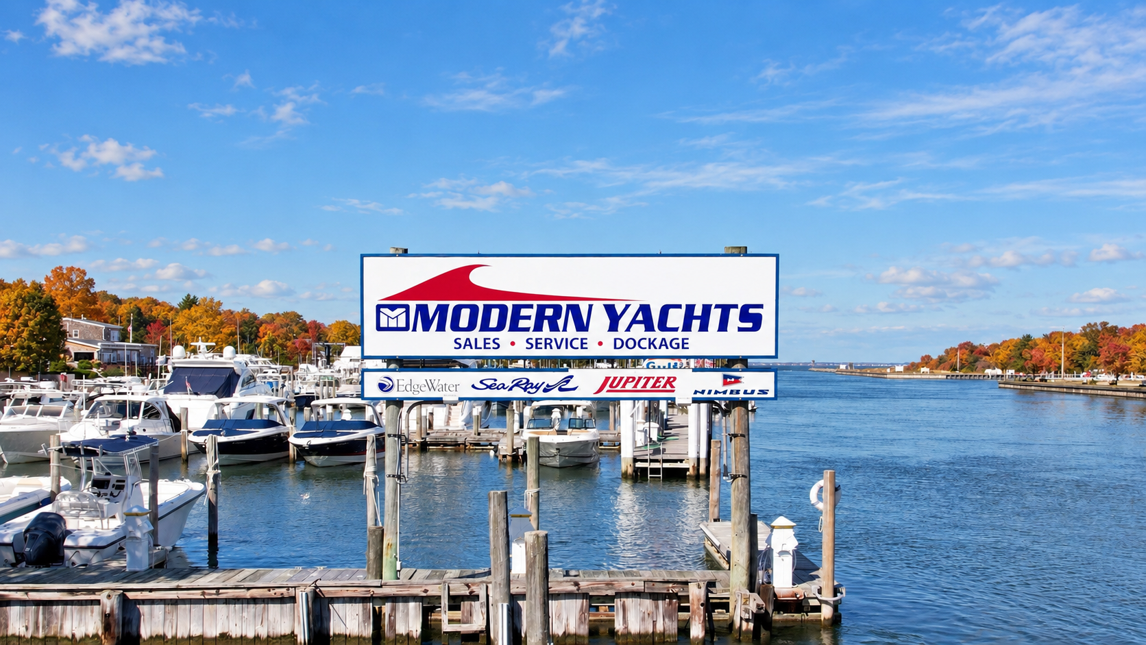 Modern Yachts marina in Hampton Bays with docked boats, waterfront signage and autumn foliage.